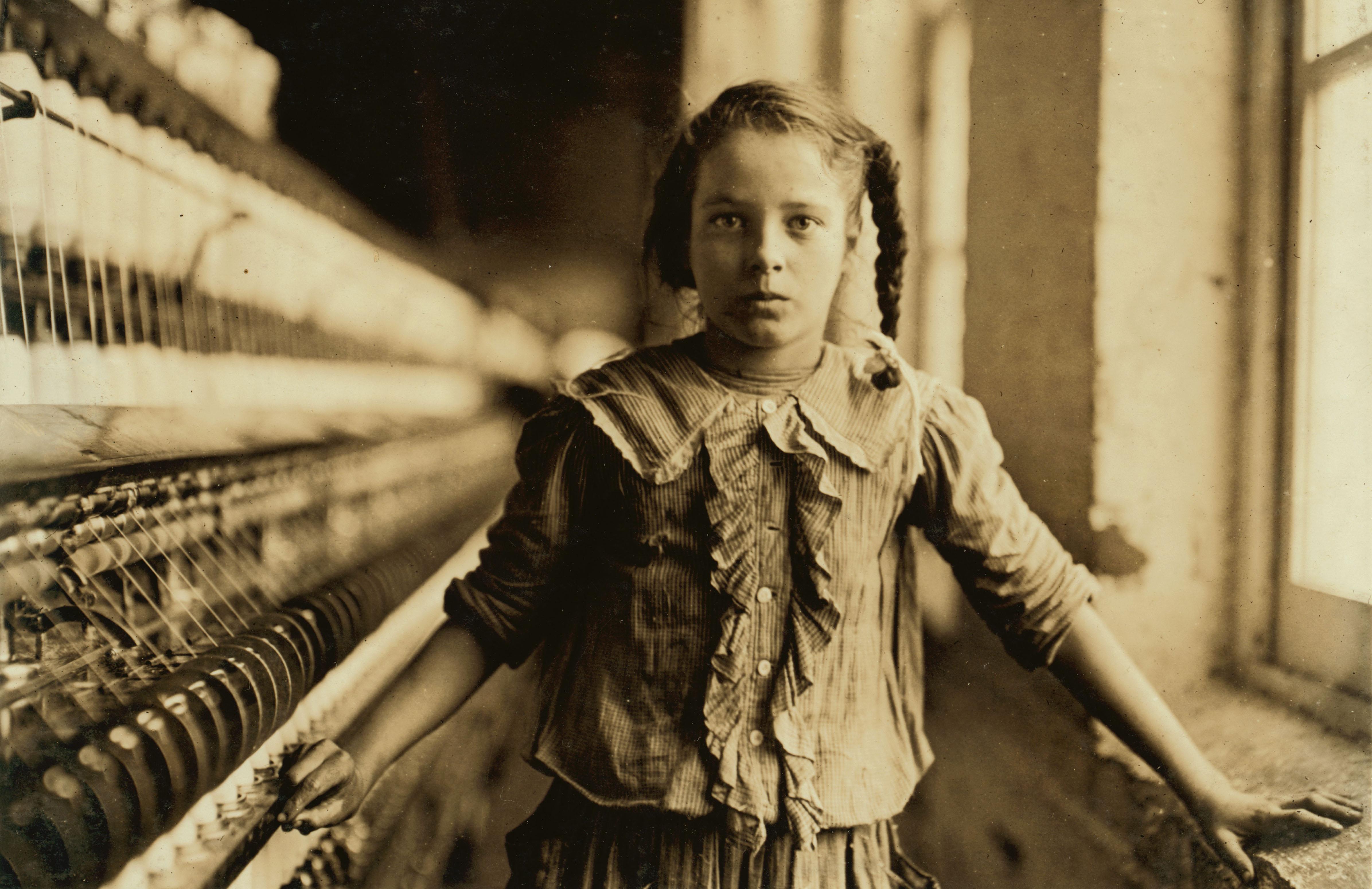 Young girl working at a spinning machine in a textile mill, 1908 by Lewis Hine