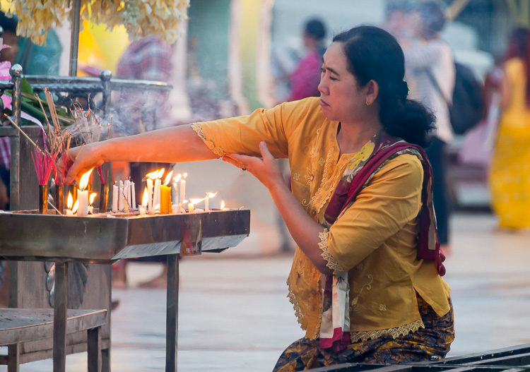 Woman lighting incense in a famous Yangon landmark, the Shwedagon Pagoda