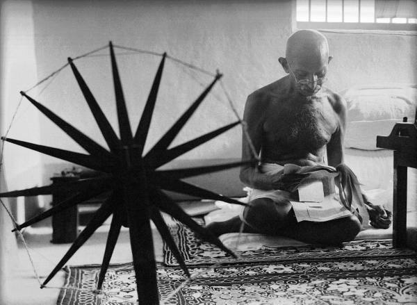 the last portrait of Ghandi sitting cross legged on the floor spinning yarn