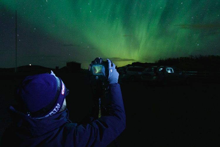 photographer out at night learning how to photograph the aurora borealis