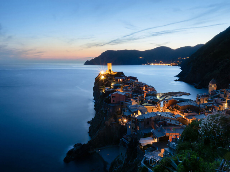 stunning blue hour landscape photo of houses and the ocean with coastline in the distance showing the colors of sunset