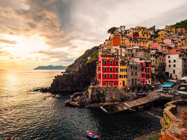 colorful houses and buildings along the coast with small boat in this landscape photo taken during golden hour