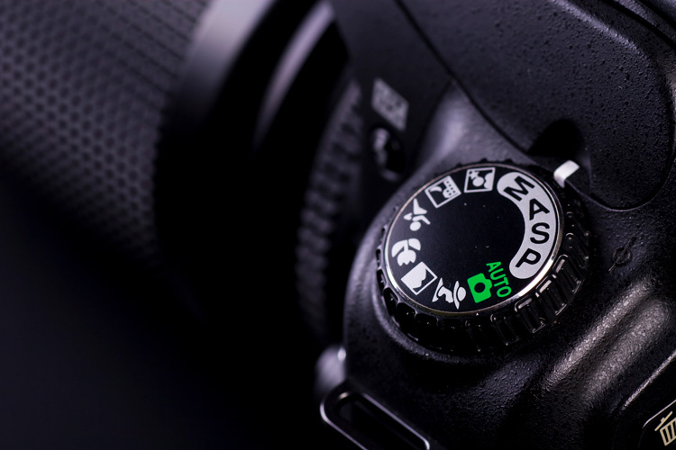 Close up of camera mode settings button on a Nikon camera showing camera modes to choose from