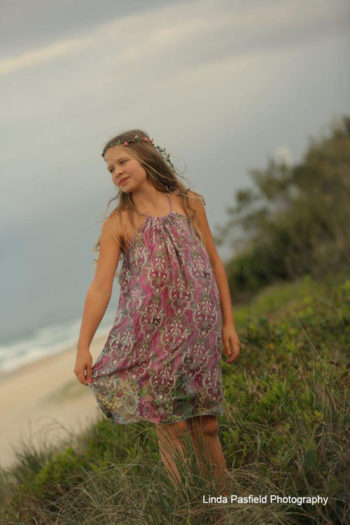 camera shy girl poses in her dress at the beach