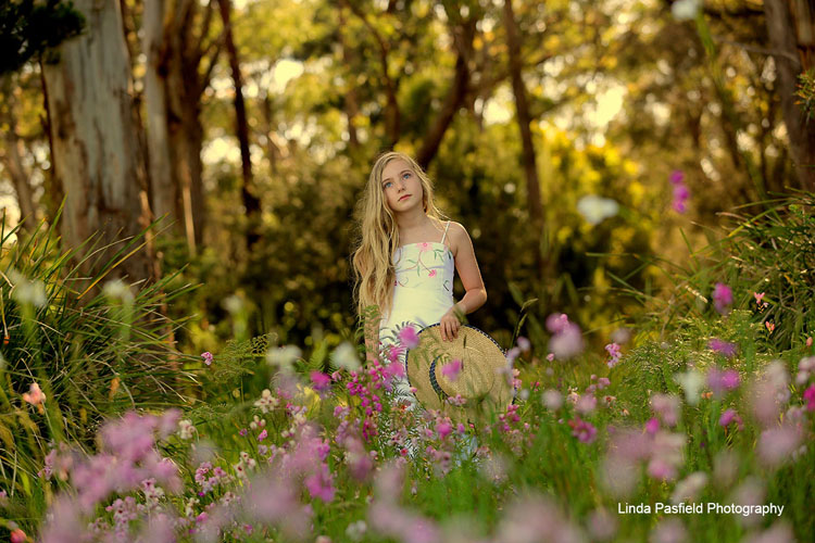 young model posing while surrounded by trees and flowers