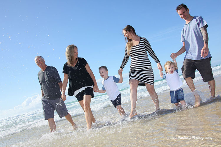 a family walks together in the surf holding hands making the children feel more comfortable in front of the camera