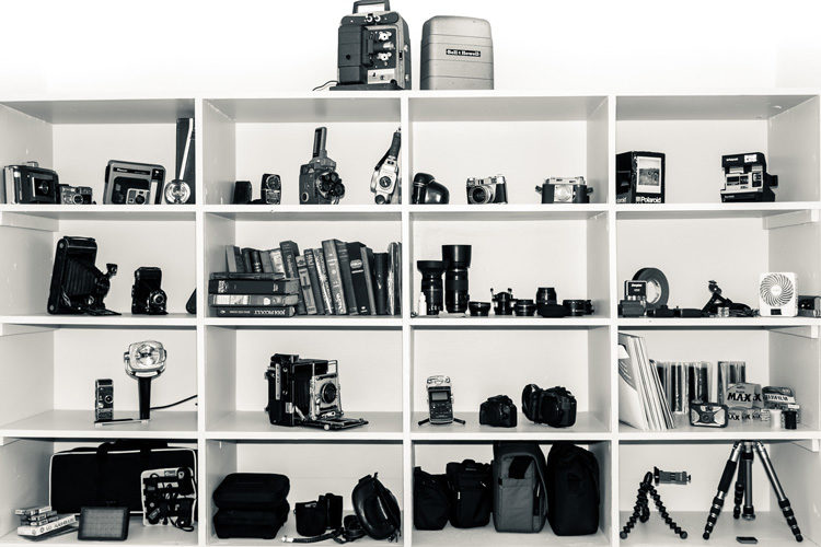 a shelf filled with old cameras collecting dust