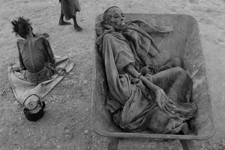 Somalian woman in a wheelbarrow waiting to be taken to a food station during the famine of 1992.