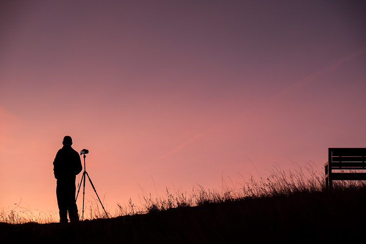 Silhouette of a photographer against a vivid sunset sky
