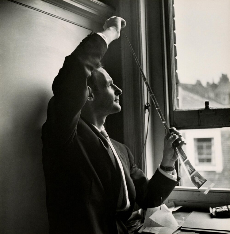 black and white photo of famous portrait photographer Irving Penn reviewing a strip of negatives