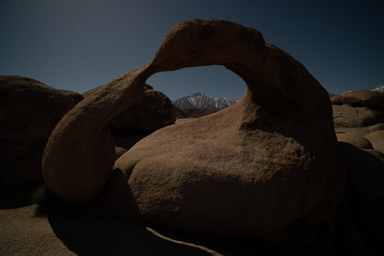 night photo of a stone arch lit with only ambient moon light
