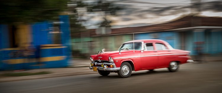 a slower shutter speed along with panning technique creates this blurred photo of a classic car in Havana Cuba