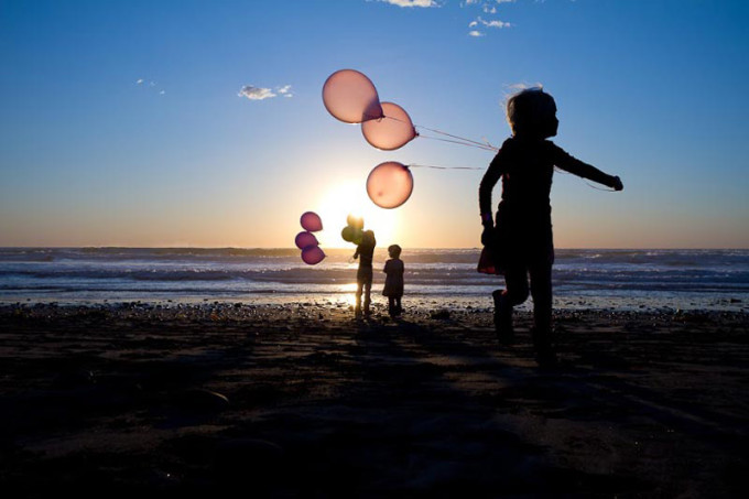 children with balloons in silhouette