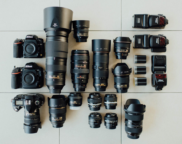 an assortment of camera gear including bodies, lenses and flashes