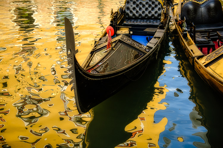 reflections of a building in the water with gondolas