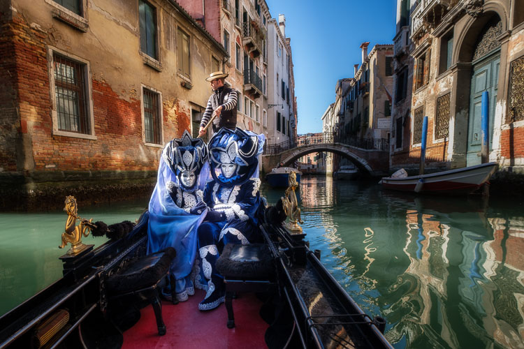 Costumed and masked characters in gondola on Venice canal