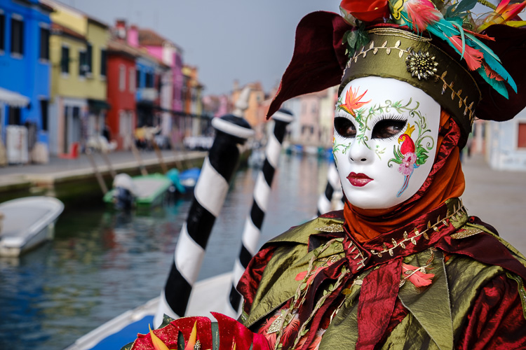costumed character alongside a canal in Venice during Carnival