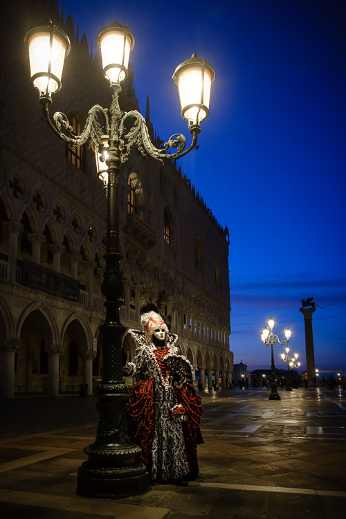 Costumed character poses at morning blue hour under an old fashioned street lamp in St Marks square