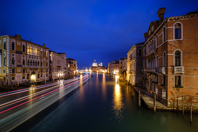 boat light trails in a canal in venice at night as blue hour develops