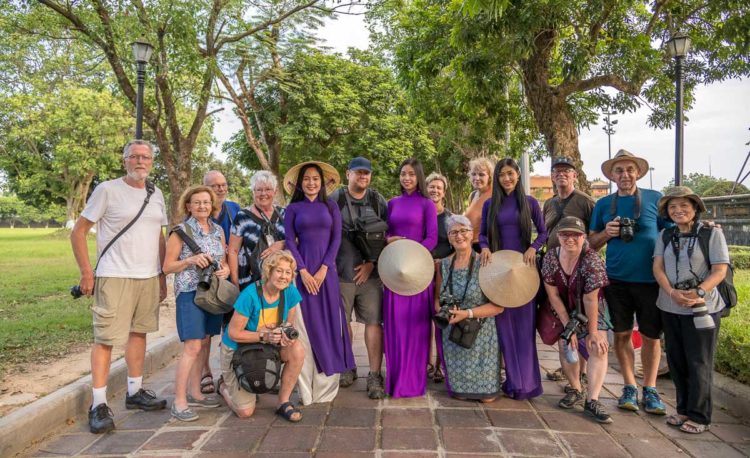 Vietnam photo tour group poses for their group shot with local Vietnamese women dressed in traditional clothing