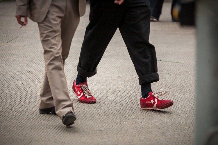 Two people walking with contrasting styles and colors of footwear are shown in this creative photo idea