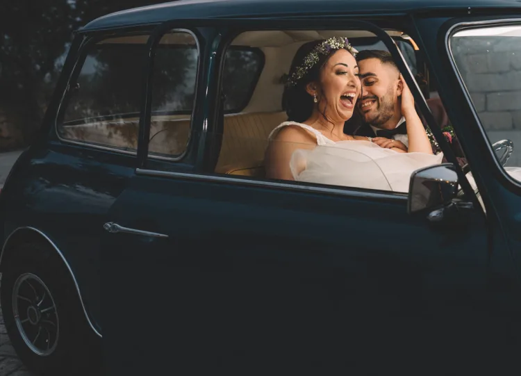 Portrait of newlyweds in front seat of a car