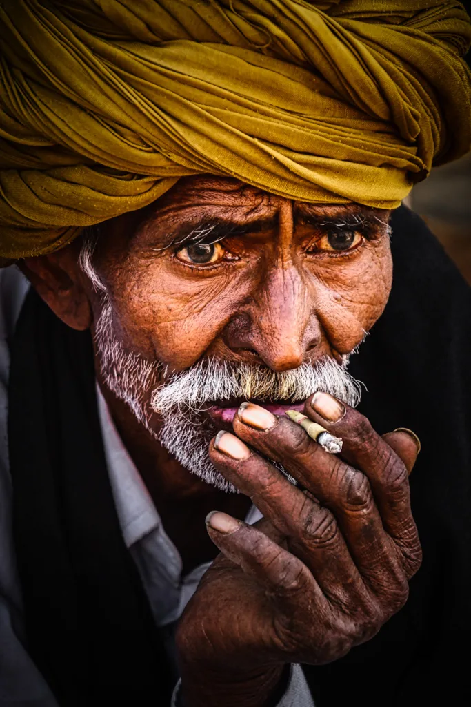 Telephoto lens used to photograph an Indian man smoking a hand rolled cigarette creates a dramatic look